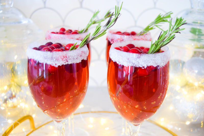 christmas cocktails with champagne, cranberry pomegranate juice, rosemary, and frozen cranberries