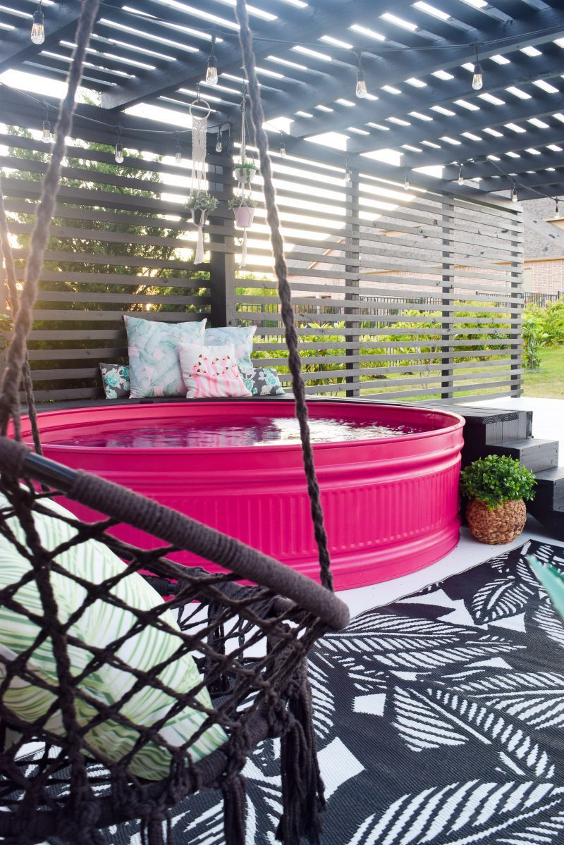 stock tank pool painted pink and hanging swing on patio deck