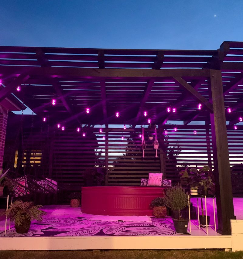 pink stock tank pool on black and white deck with pink string lights